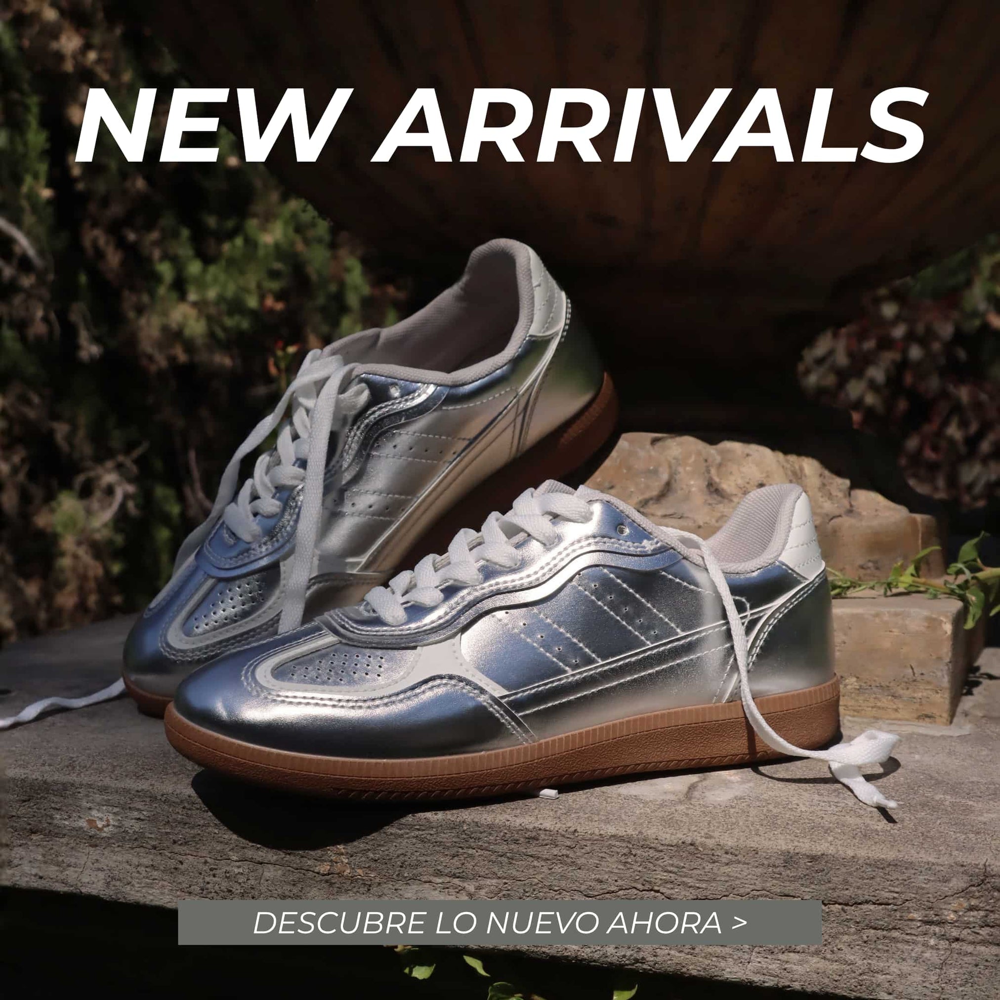 Tenis plateados para mujer Gotta México de nueva colección con acabado metalizado y suela color caramelo, exhibidos sobre una base de piedra en un entorno exterior.